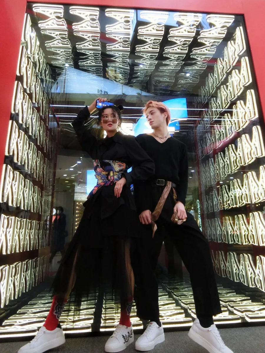 Two people beside a sneaker-themed infinity mirror installation