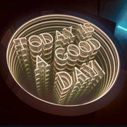 The Maytrix "Today Is A Good Day" Infinity Mirror features white LED lighting that forms the phrase and creates a tunnel-like effect with multiple reflections, making it a striking and inspirational décor piece.