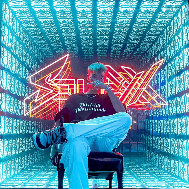 A person seated inside an illuminated infinity mirror installation